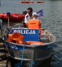 policjant wraz z dzieckiem na policyjnej motorówce