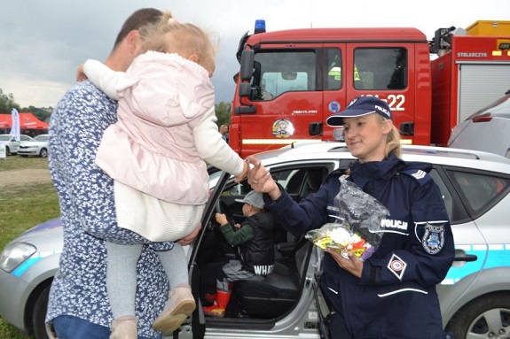 policjantka wręcza dziecku informator akcji Kręci mnie bezpieczeństwo nad wodą