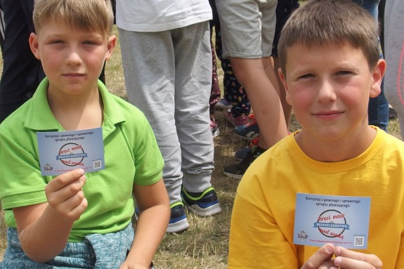 Dzieci pokazują naklejki z zasadami bezpiecznego zachowania nad wodą w ramach akcji &quot;Kręci mnie bezpieczeństwo nad wodą&quot;
