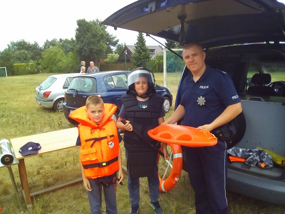 Policjant wręcza dzieciom gadżety związane z bezpieczeństwem nad wodą