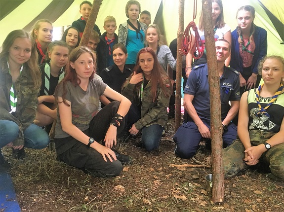 Policjant przekazuje młodzieży zasady bezpiecznego zachowania nad wodą.