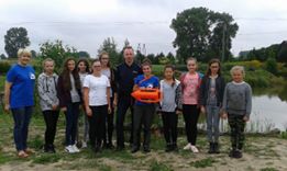 Policjant przekazuje dzieciom zasady bezpiecznego zachowania nad wodą.