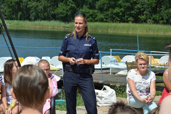 Policjantka przekazuje dzieciom zasady bezpiecznego zachowania nad wodą.