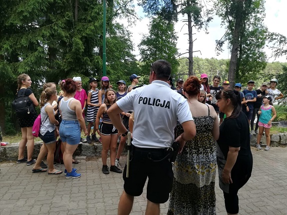 Policjant przekazuje dzieciom zasady bezpiecznego zachowania nad wodą.