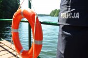Koło ratunkowe oraz policjant obserwujący wodę.