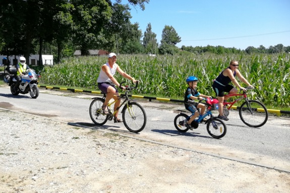 Rodzina jedzie drogą na rowerach.