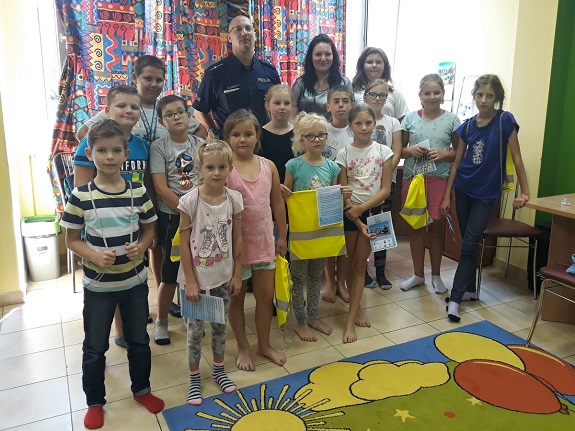 Policjant przekazuje dzieciom zasady bezpiecznego zachowania nad wodą.