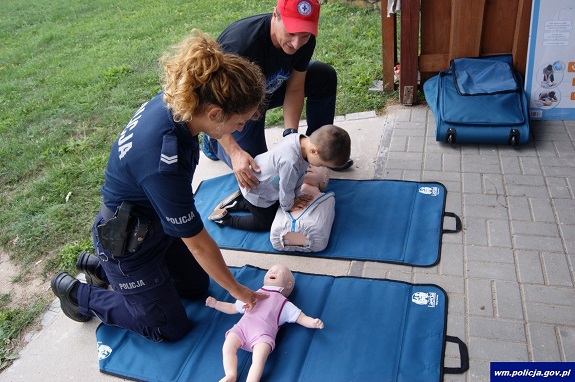 Policjanci na manekinach pokazują jak udzielać pierwszej pomocy.