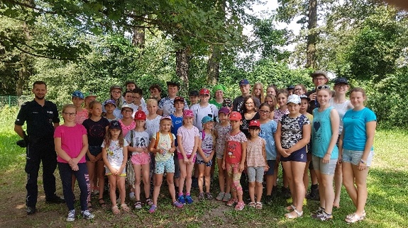 Policjant przekazuje dzieciom zasady bezpiecznego zachowania nad wodą.