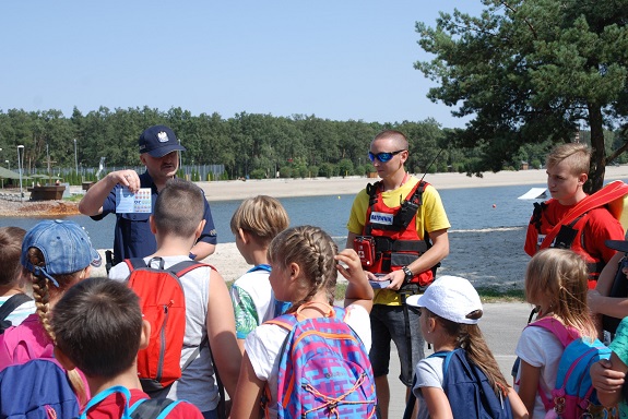 Policjant przekazuje zasady bezpiecznego zachowania nad wodą.