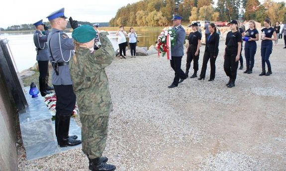 uczestnicy wyprawy składają wieniec kwiatów