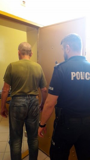 policjant prowadzi zatrzymanego