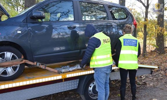 funkcjonariusze przy aucie na lawecie zabezpieczają narkotyki