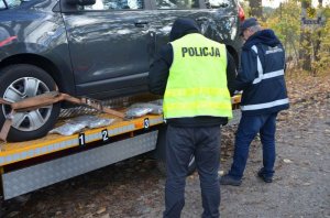 funkcjonariusze przy aucie na lawecie zabezpieczają narkotyki