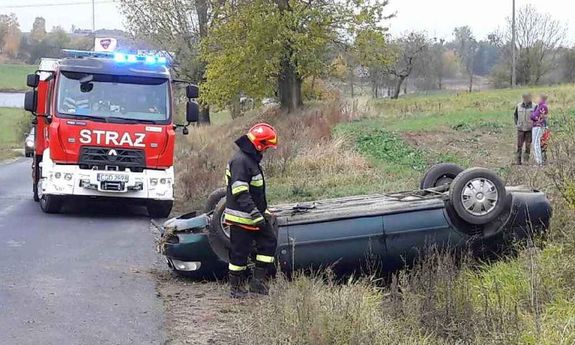 strażak przy samochodzie w rowie