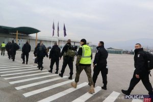 policjanci  idą w stronę terminalu lotniczego