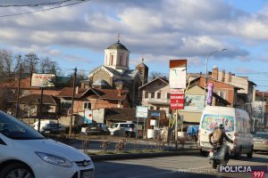 ulica miasta, widoczny kościół z krzyżem na dachu, auta, ruch uliczny