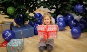 Dziewczyna siedzi pod choinkami z prezentami