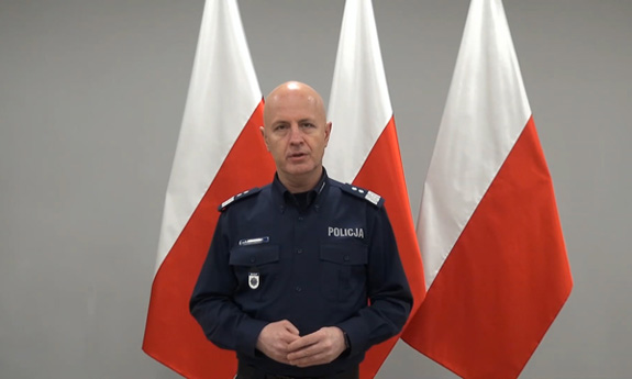 Komendant Główny Policji, w tle trzy biało-czerwone flagi