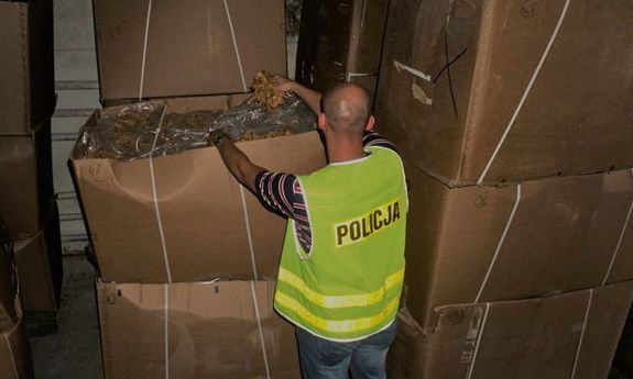 policjant z zabezpieczonymi kartonami z tytoniem
