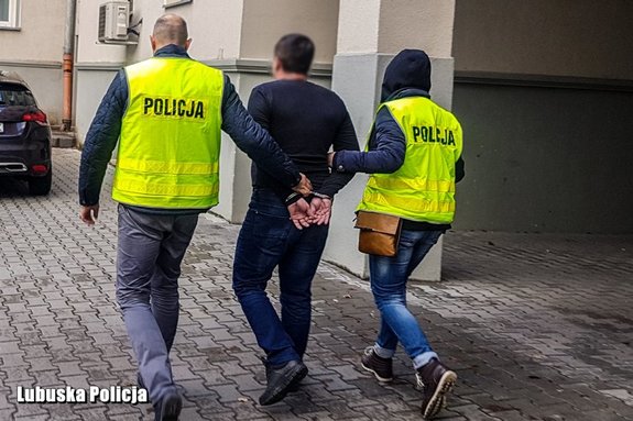 Dwóch policjantów prowadzi zatrzymanego