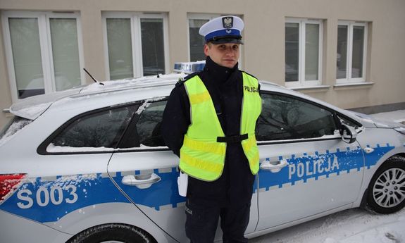 Policjant na tle radiowozu