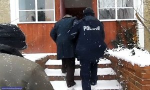 policjant pomaga  starszemu mężczyźnie wejść do domu po ośnieżonych schodach