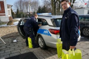 dwaj policjanci z prezentami przy radiowozie