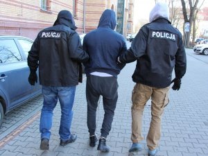 dwaj policjanci prowadzą zatrzymanego mężczyznę