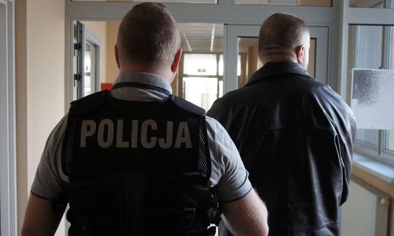 policjant prowadzi zatrzymanego