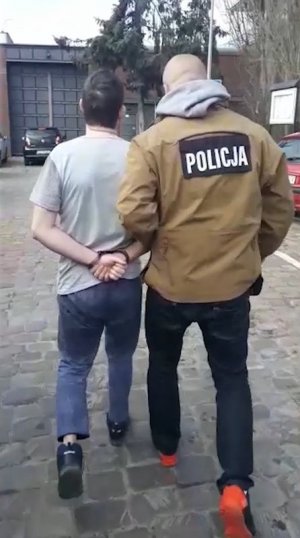 policjant prowadzi zatrzymanego