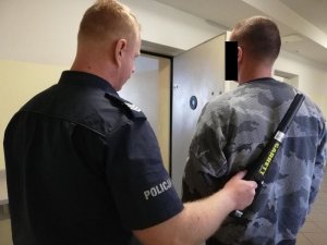 policjant prowadzi zatrzymanego