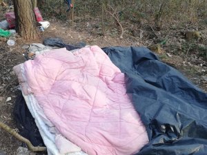 śpiwory i inne rzeczy osób bezdomnych leżące w lesie