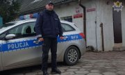 policjant Rafał Waśko w mundurze na tle radiowozu