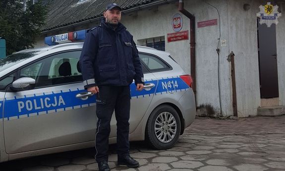 policjant Rafał Waśko w mundurze na tle radiowozu