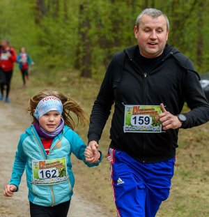 Mężczyzna trzymający za rękę dziewczynkę razem z nią zmierza do mety biegu IV Wielkanocnej Mili Namysłowian