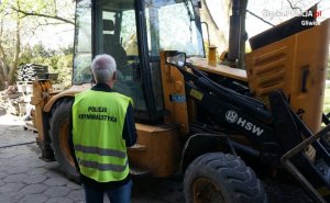 policjant w kamizelce z napisem &quot;Policja kryminalistyka&quot;, przed skradzioną koparką