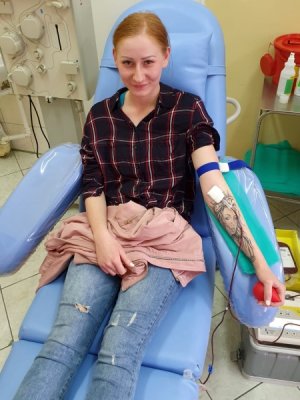 Policjanta na fotelu oddaje honorowo krew w stacji krwiodawstwa.
