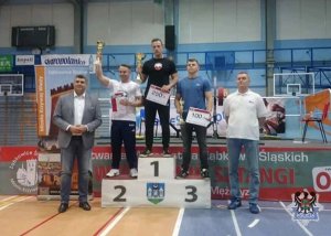 Trzej zawodnicy na podium z dyplomami, pucharami i medalami