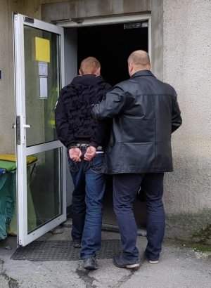policjant kryminalny doprowadza zatrzymanego do jednostki