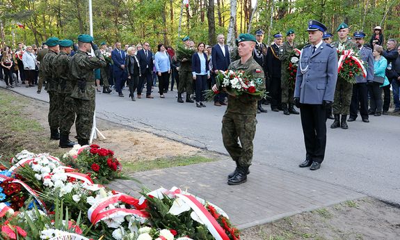 podinsp. Horosz składa kwiaty przed tablicą pamiątkową