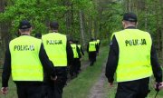 grupa policjantów w żółtych kamizelkach podczas poszukiwań w lesie