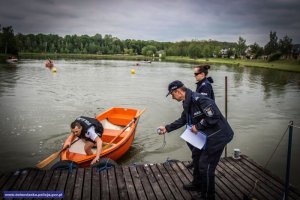 zawodnik wysiada z łódki, pomagają mu dwaj policjanci którzy stoją na pomoście
