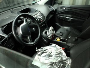 Wnętrze samochodu, zdjęcie zrobione od strony szyby kierowcy. Widać częściowo rozmontowaną okolicę dźwigni zmiany biegów