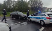 Policjanci przy radiowozach policyjnych  na drodze nr 8 podczas zatrzymania poszukiwanego mężczyzny