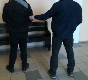 policjant ubrany po cywilnemu prowadzi zatrzymanego