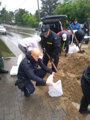 grupa policjantów nasypuje piasek do worków