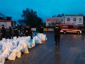 worki z nasypanym piaskiem, grupa strażaków i policjantów, którzy nasypują piasek do worków