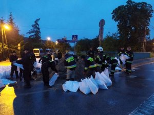 worki z nasypanym piaskiem, grupa strażaków i policjantów, którzy nasypują piasek do worków