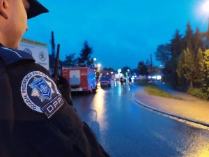 policjant z oddziału prewencji w tle wozy strażackie